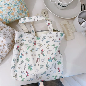 Detailed close-up of cream canvas tote bag with floral bunny print and zipper closure