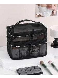 Detail of black mesh double-layer makeup bag with handle and dual zippers on white stand