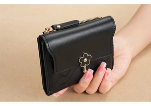 Detailed close-up of a black PU leather wallet featuring floral charms and quilted texture