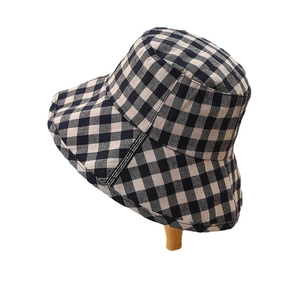 Classic black and white gingham bucket hat with decorative ribbon on a wooden stand