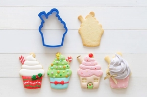 Blue cupcake-shaped cookie cutter with finished Christmas house and snowman biscuits