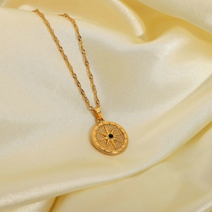 Golden stainless steel starburst pendant necklace with black center on beige silk fabric
