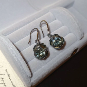 Gros plan de boucles d'oreilles vintage avec strass gris sur du velours gris