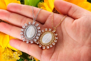 Detailed close-up of Virgin Mary pendants in gold and silver with zircon inlays