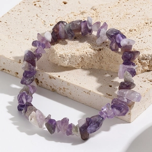 Macro shot of natural amethyst stone stretch bracelet on beige textured stone base