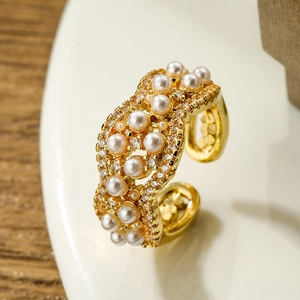 Gold plated wave ring with white pearls and zircons on elegant ceramic background