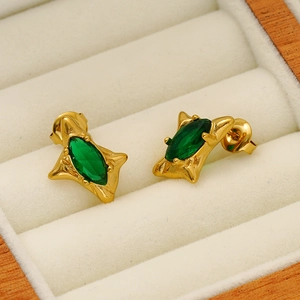Boucles d'oreilles vintage acier doré avec zircon vert sur velours beige
