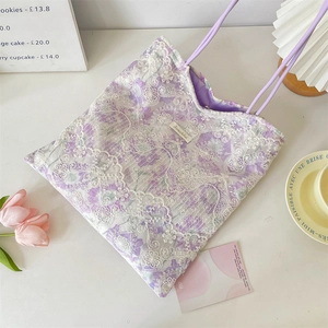 Detail view of purple floral canvas tote with white lace embroidery and brand label