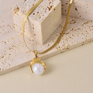 Detailed macro view of a gold pearl pendant on a sleek flat snake bone necklace chain