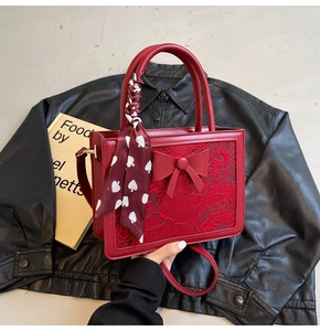 Detail of red bridal handbag with lace texture, large bow, and silk scarf handle wrap