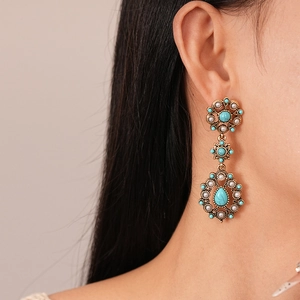Close-up of vintage flower earrings with turquoise and pearls on model