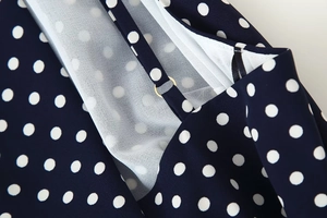 Detailed close-up of dark blue polka dot fabric with white lining and gold buckle