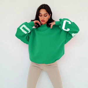 Détail du sweat-shirt vert oversize montrant l'imprimé lettres C et D sur les manches