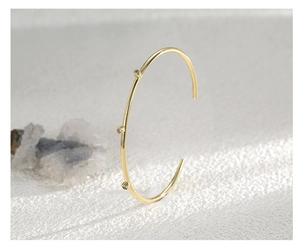 Macro side view of an adjustable gold-plated brass cuff with three cubic zirconia stones