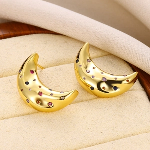 Macro shot of gold crescent moon earrings with colorful zircon stones in a jewelry box