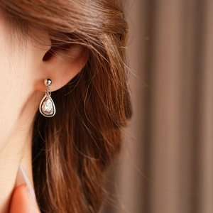 Close-up of a silver teardrop earring with sparkling zircon inlay worn by a model
