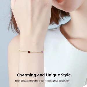 Close-up of a delicate gold chain bracelet with colorful round-cut gemstones on a wrist