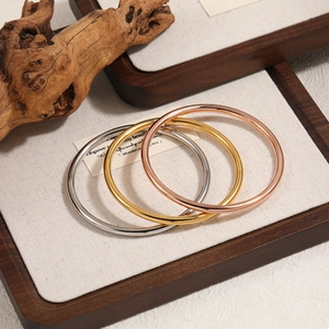 Sleek 4mm solid metal bangles in silver, gold, and rose gold on a rustic wood display