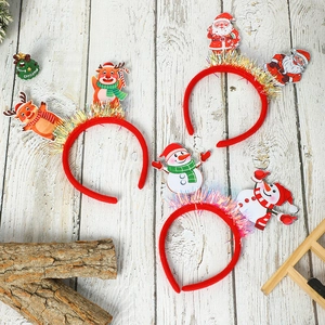 Three festive Christmas headbands with Santa, Snowman, and Reindeer on a white wood background