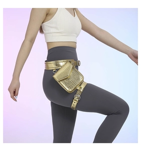 Détail du sac de jambe doré motif crocodile avec finition métallique porté par un modèle