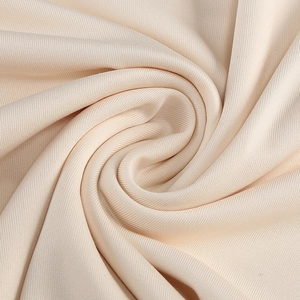 Macro shot of champagne gold elastic knit fabric with premium draped texture and smooth finish