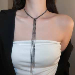 Dettaglio di una collana a più strati con nappe in metallo nero indossata da una modella