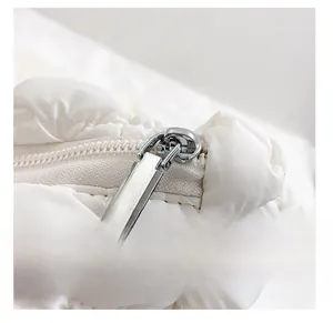Macro detail of the smooth silver zipper and quilted white fabric on this cloud bag