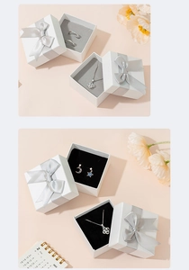 White jewelry gift box with silver ribbon bow featuring ring, necklace, and earrings