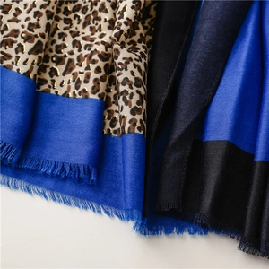 Detail of leopard print scarf with gold foil accents and blue color blocking fringe
