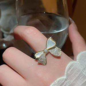 Close-up of 14k gold plated bow ring with white mother-of-pearl and sparkling zircon inlay
