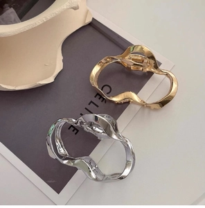 Detailed view of polished silver and gold wave metal hair clips on art magazine