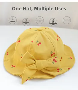 Detail of yellow cotton baby sun hat with red cherry print and a large bow decoration