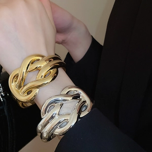 Macro detail of intertwined metal knot bracelets in high-polished gold and silver finish