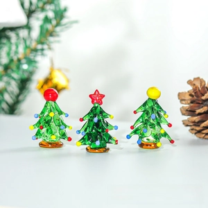 Detail of three mini handcrafted green glass Christmas trees with colorful ornaments