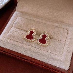 Gros plan de boucles d'oreilles gourde plaquées or avec œil de tigre rouge et strass