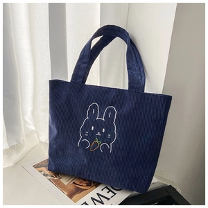 Detail view of navy blue corduroy handbag featuring a cute white rabbit embroidery