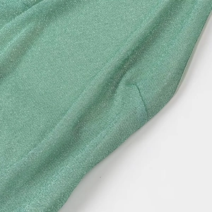 Close-up of green shimmering fabric with glitter texture on sexy halter party dress