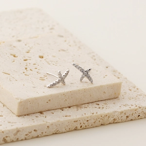 Macro shot of silver S925 sterling silver X-shaped geometric stud earrings with diamonds