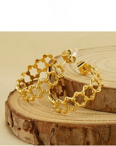 Dettaglio di orecchini esagonali placcati oro 18K con design geometrico traforato