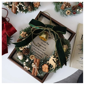 Detail of a Christmas wreath with green velvet bow, golden bells, and cinnamon sticks
