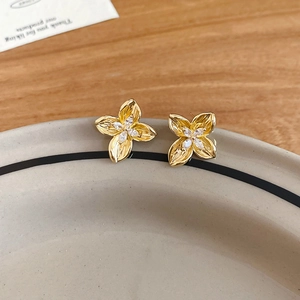 Close-up of gold flower earrings with marquise-cut zircon stones on ceramic plate