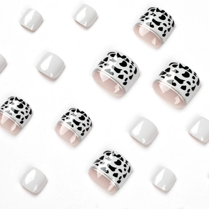 Press-on toenails featuring cow print patterns and solid white with silver line accents