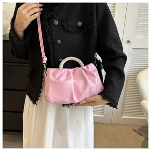 Lifestyle shot of pink pleated crossbody bag with elegant pearl handle on a model