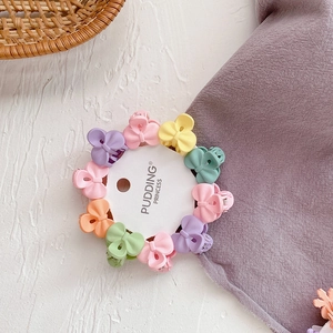 Close-up of candy-colored mini bow hair clips set on a white circular card display