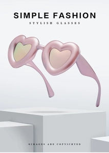 Pink heart-shaped sunglasses with satin metallic frame on a minimalist stone pedestal
