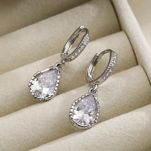 Elegant silver teardrop earrings with sparkling cubic zirconia on a beige velvet base
