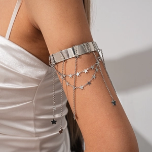 Detail of silver star tassel upper arm cuff on a model with white satin fabric