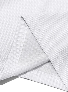 Detailed macro view of white waffle knit fabric texture and fine stitching on the shirt