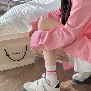 Detail of white striped socks and casual shoes shown in a soft indoor bedroom setting
