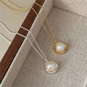 Close-up of elegant gold and silver freshwater pearl necklaces on a textured surface